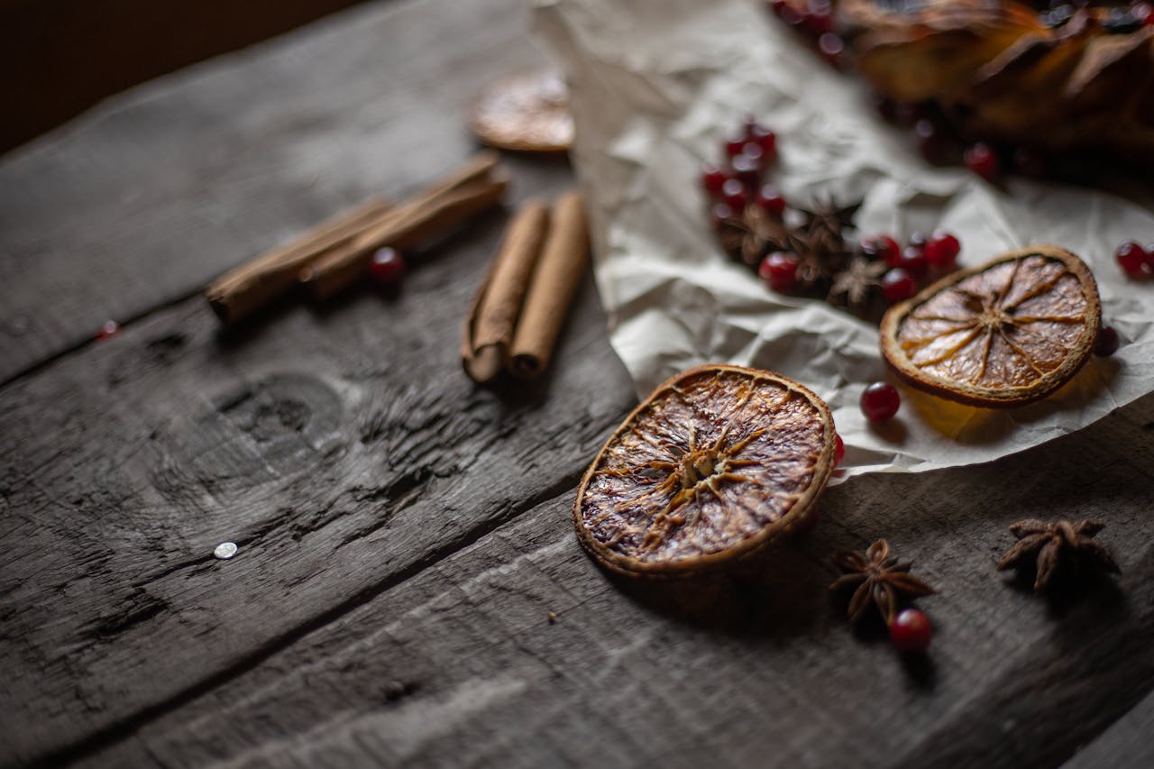 about-01 A rustic still life of dried orange slices, cinnamon sticks, and star anise on a wooden table.